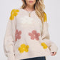 Cream-colored oversized knit sweater with fluffy yellow and pink floral appliques by Jade by Jane