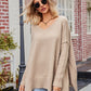 Beige oversized V-neck sweater with slit exposed seams and ribbed cuffs