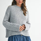 Cozy light gray ribbed knit sweater with frayed hem on denim shorts