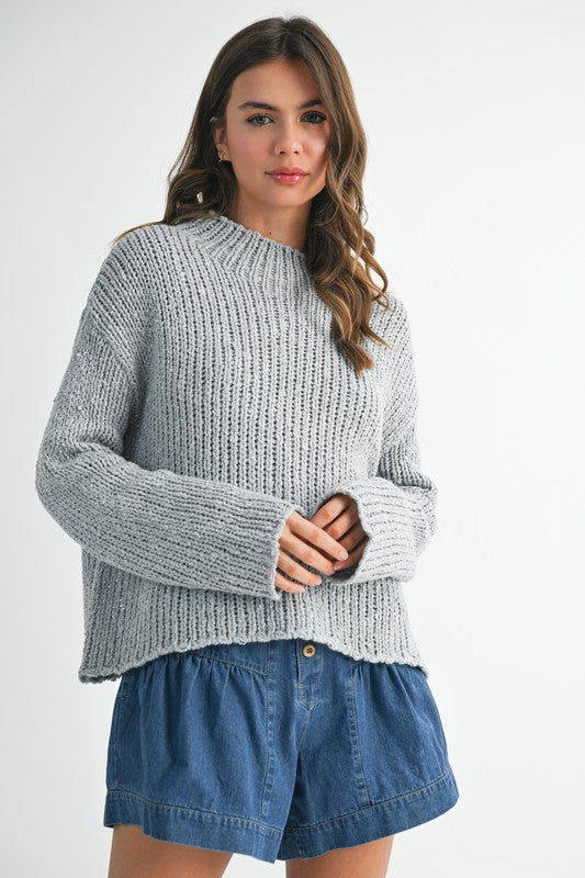 Cozy light gray ribbed knit sweater with frayed hem on denim shorts