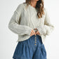 Light gray cable-knit sweater with cozy texture on denim shorts
