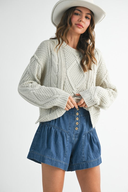 Light gray cable-knit sweater with cozy texture on denim shorts