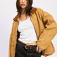 Woman wearing a tan jacket over a white top and black skirt on a white background