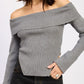 Woman wearing a gray off-shoulder sweater against a white background