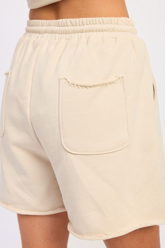 Cream-colored French terry shorts with pockets, relaxed fit, elastic waistband