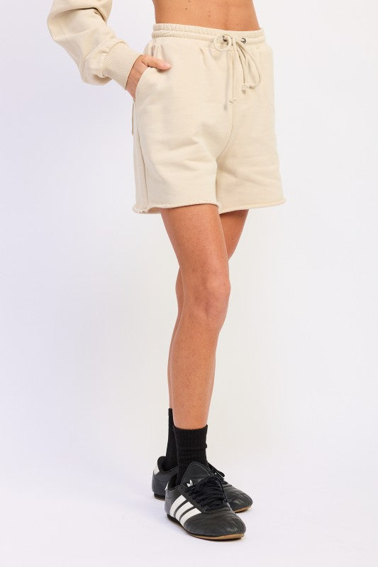 Beige French terry drawstring shorts with pockets and frayed hem