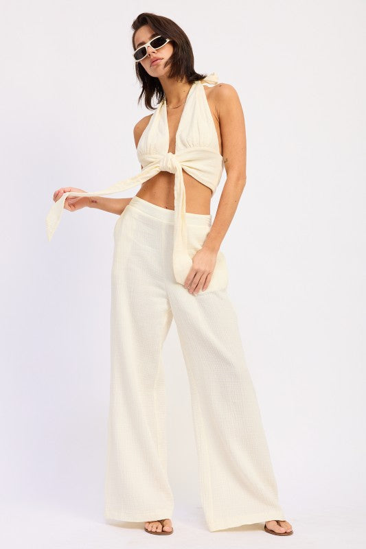Cream-colored satin double gauze halter neck crop top with tied knot and wide-leg trousers
