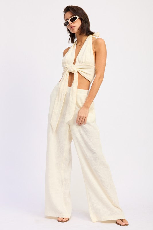 Cream-colored satin halter crop top with knot and cutouts, wide-leg trousers