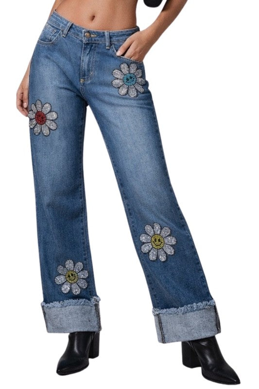 Junior Low Rise Rhinestone Daisy Jean with blue denim, embroidered smiling face floral patches and glittery details