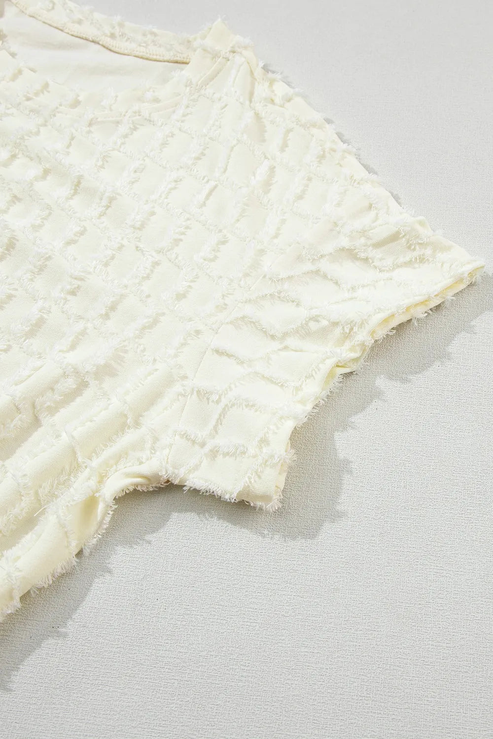 Daverri textured round neck top in cream with ruffled neckline and frayed hem