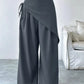 Daverri wrap-front wide-leg pants in dark gray with draped asymmetrical front and side tie detail
