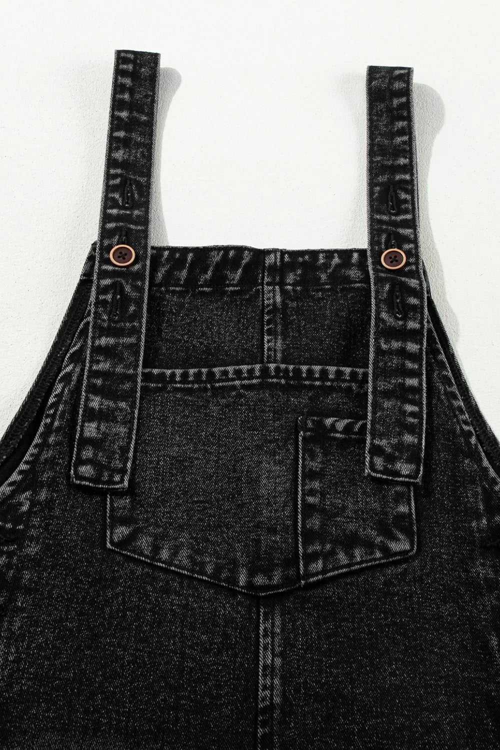 Distressed wide strap denim overalls with black denim, sturdy straps, brown buttons