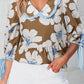 Brown floral blouse with white and light blue patterns, ruffled neckline, blue striped trim, and tie sleeves