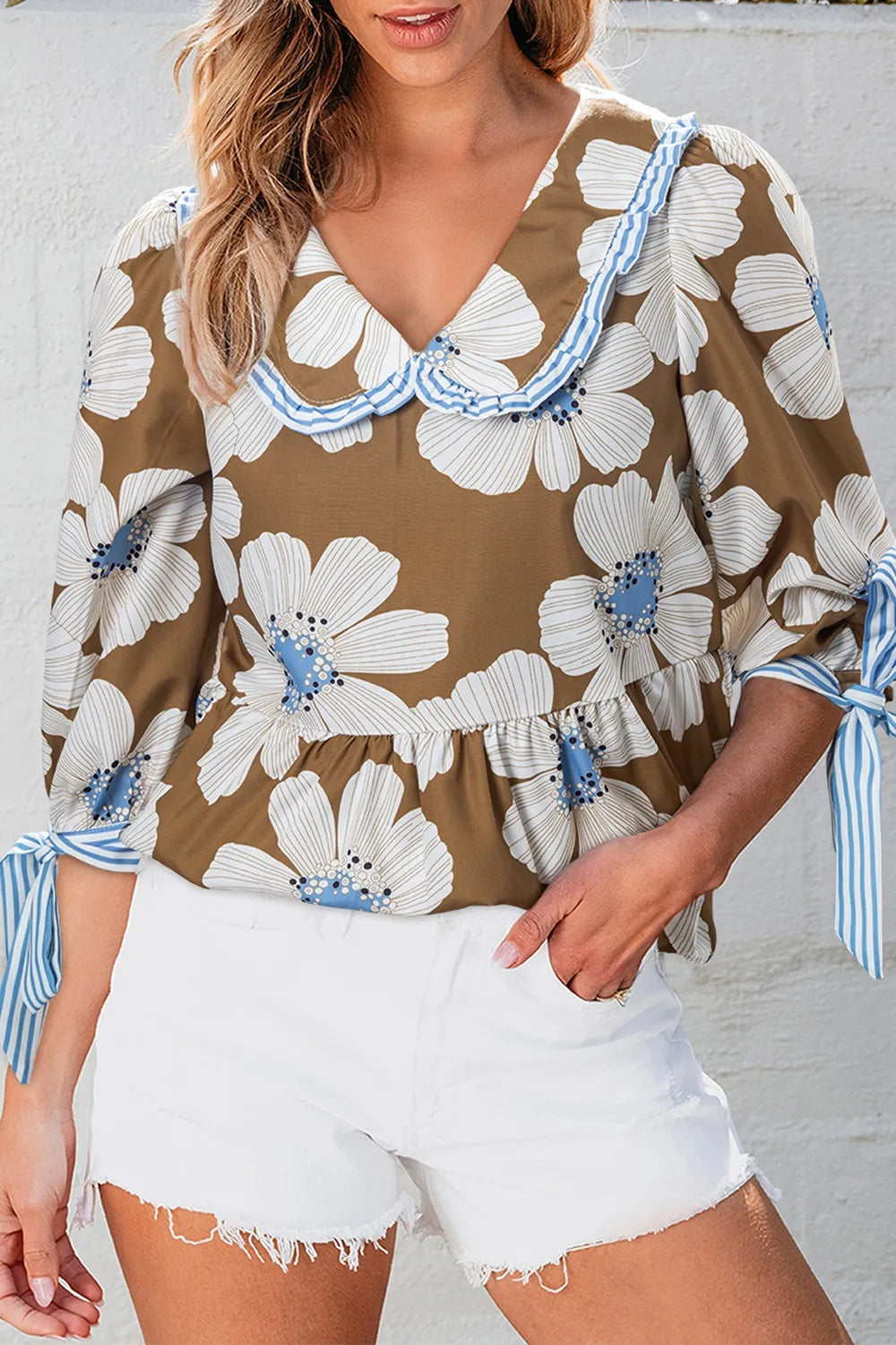 Brown floral blouse with white and light blue patterns, ruffled neckline, blue striped trim, and tie sleeves