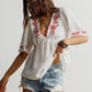 White embroidered floral V-neck blouse with red details on neckline and sleeves