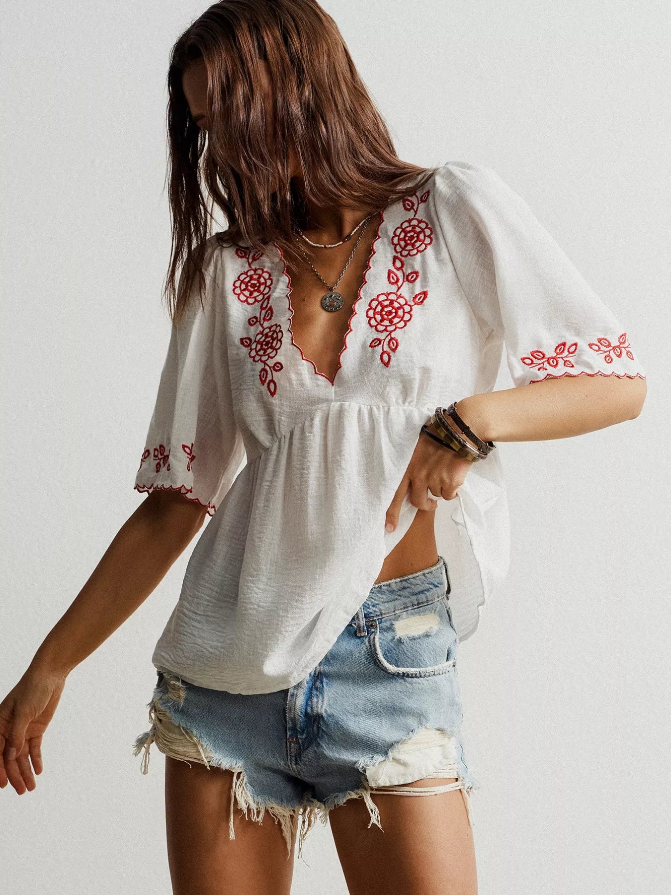 White embroidered floral V-neck blouse with red details on neckline and sleeves