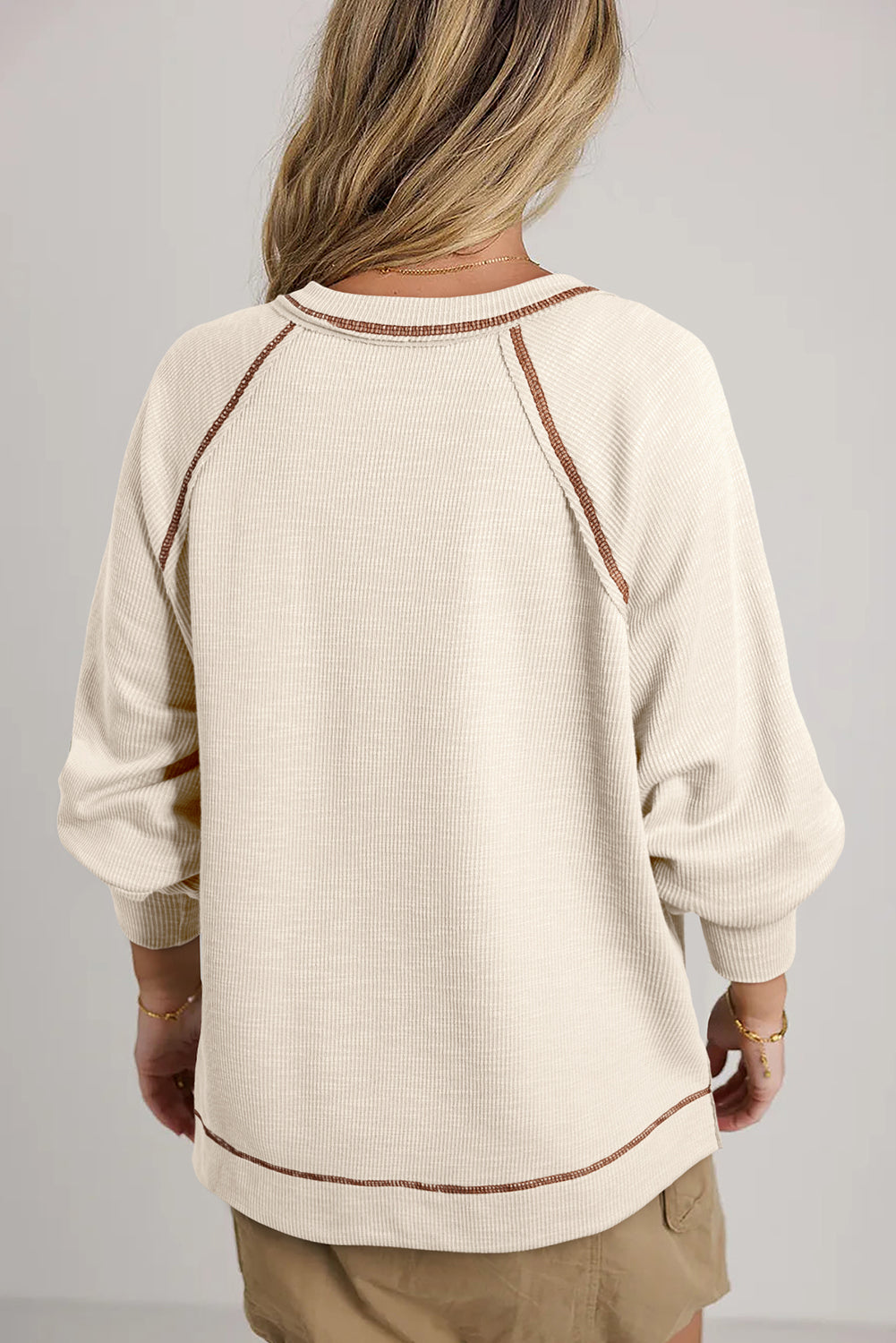 Cream-colored ribbed knit V-neck pullover with brown exposed seams