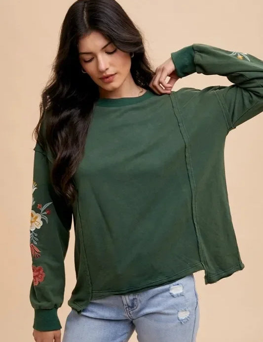 Green floral embroidered long sleeve French terry top in Black Forest with distressed jeans
