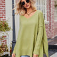 Olive-green oversized V-neck knit sweater with ribbed cuffs and slit seams
