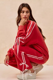 Red oversized hoodie with white stripes, drawstrings, and BiBi bow details
