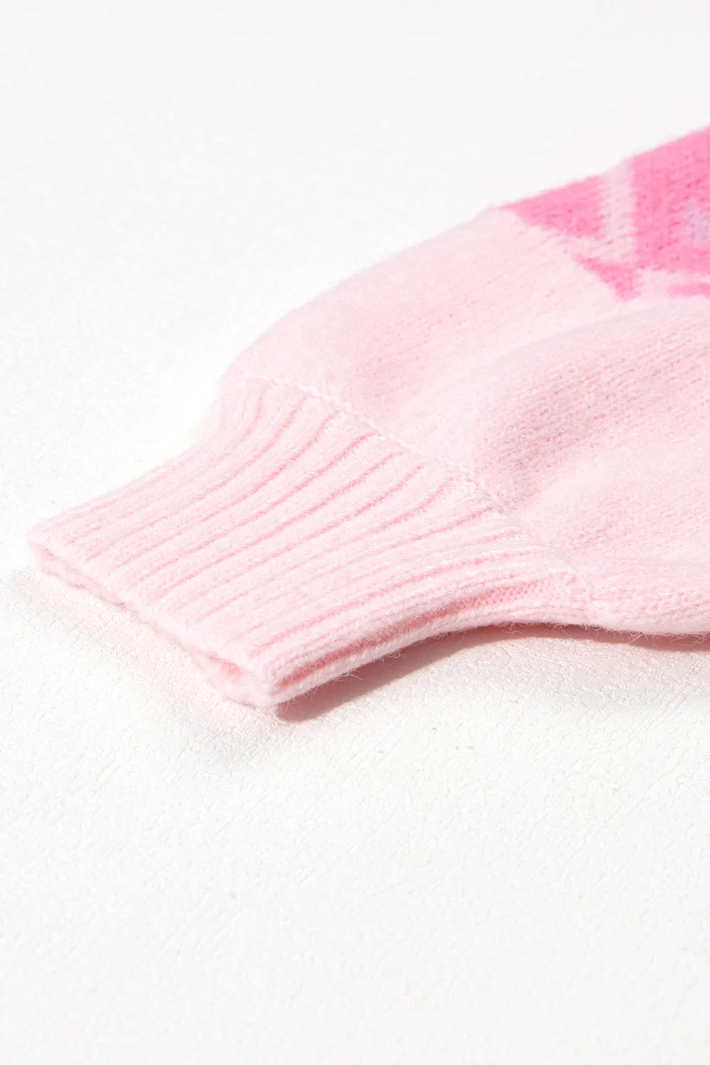 Pink ribbed knit sweater cuff with subtle geometric pattern
