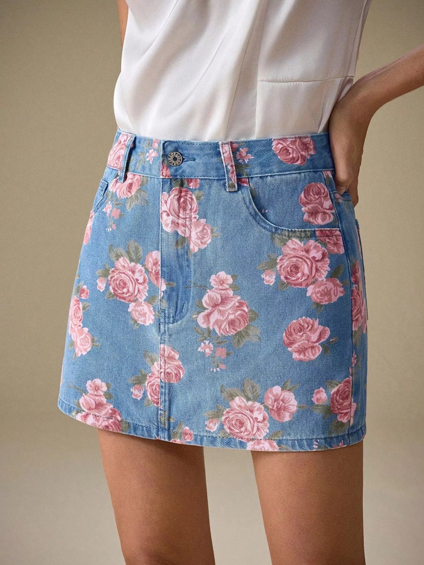 Floral print denim mini skirt with pink rose pattern on blue background