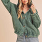 Woman wearing a green corduroy jacket and denim shorts on a beige background