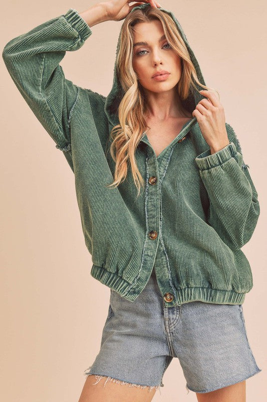 Woman wearing a green corduroy jacket and denim shorts on a beige background