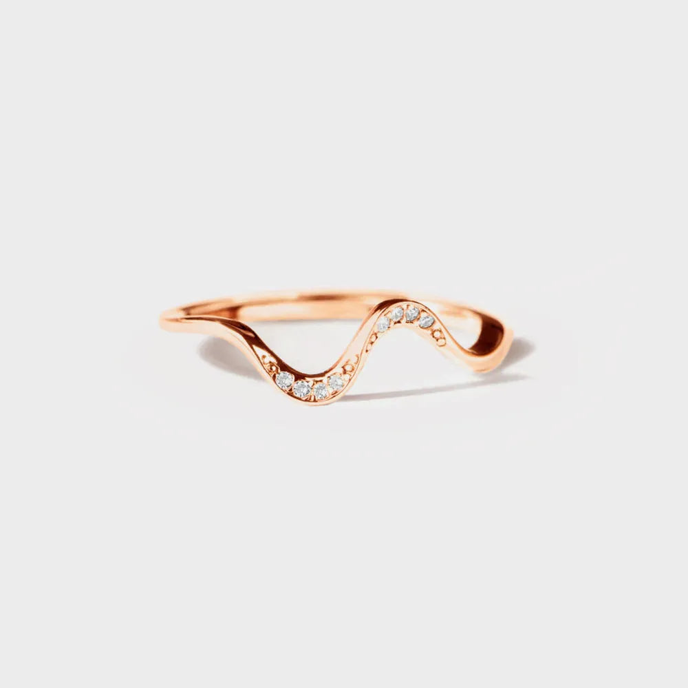 Rose gold ring with wavy design on a light gray background
