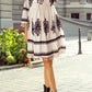 White embroidered boho mini dress with black floral patterns and tassel hem