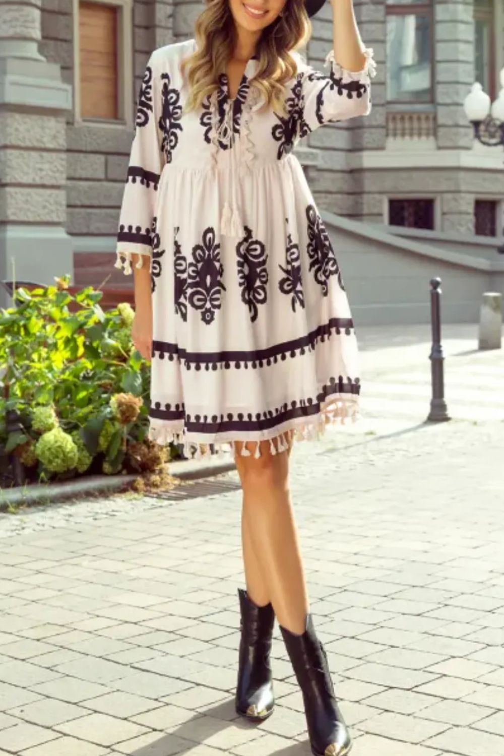 White embroidered boho mini dress with black floral patterns and tassel hem