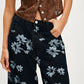 Printed wide leg jeans in black denim with silver and white floral pattern