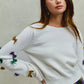 White knit sweater with colorful sequined bows on sleeves, SO ME Mardi Gras top