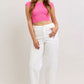 Woman in vibrant pink cropped top and Judy Blue high-waisted white jeans