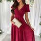 Woman in surplice short sleeve midi dress with deep red satin V-neck and flutter sleeves
