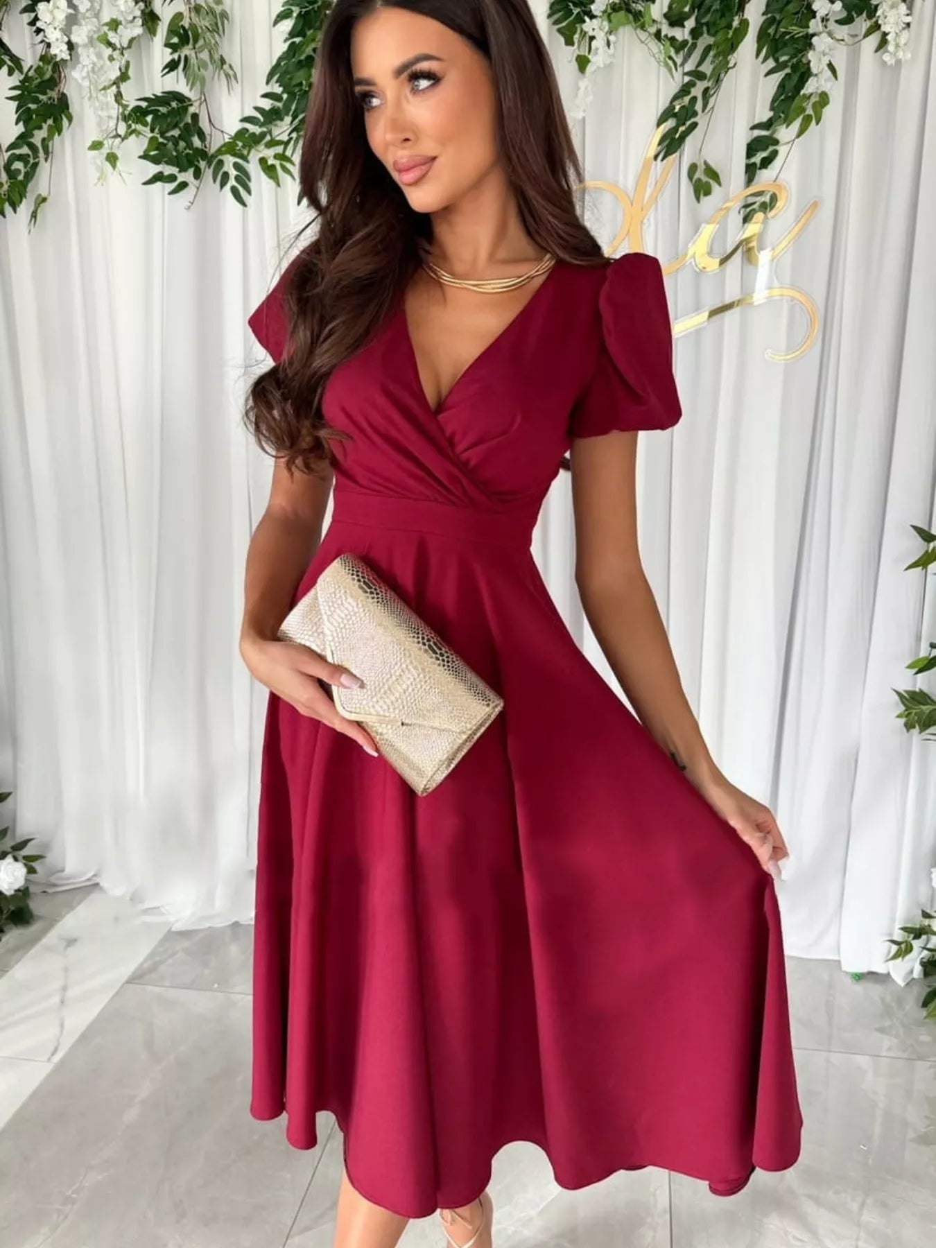 Woman in surplice short sleeve midi dress with deep red satin V-neck and flutter sleeves