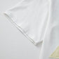 White cotton drop shoulder tee with pale yellow eyelet triangle patch