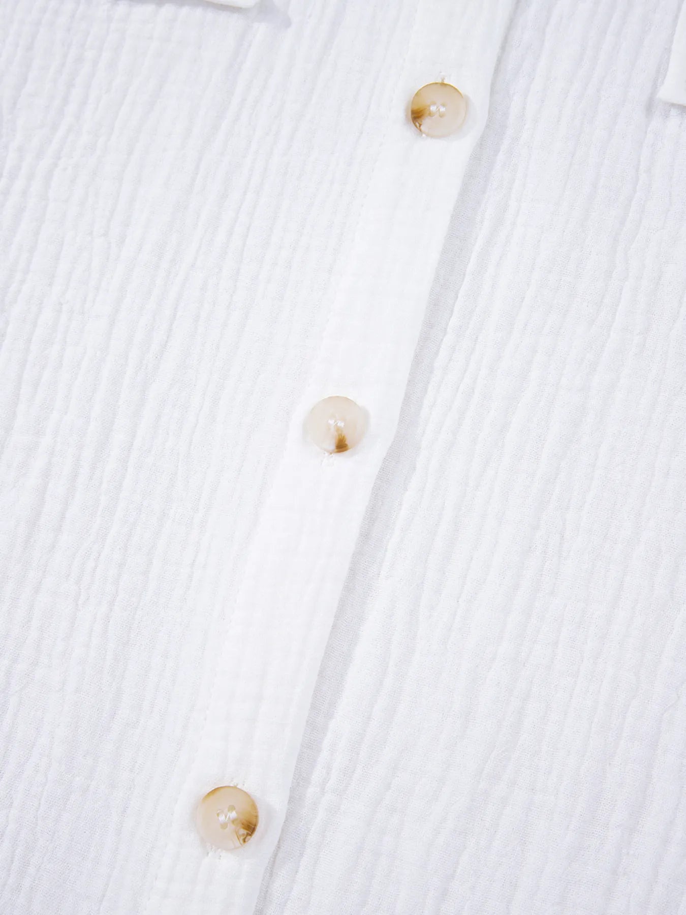 Three translucent beige buttons on women’s lace sleeve cotton shirt