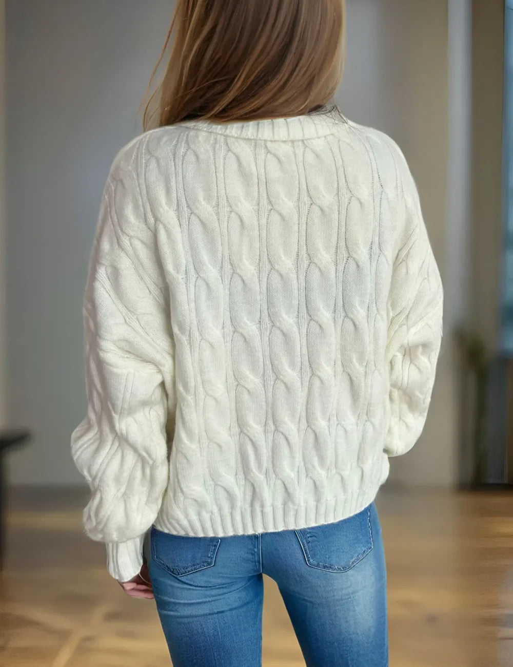Cream cable-knit turtleneck sweater with blue jeans and long hair