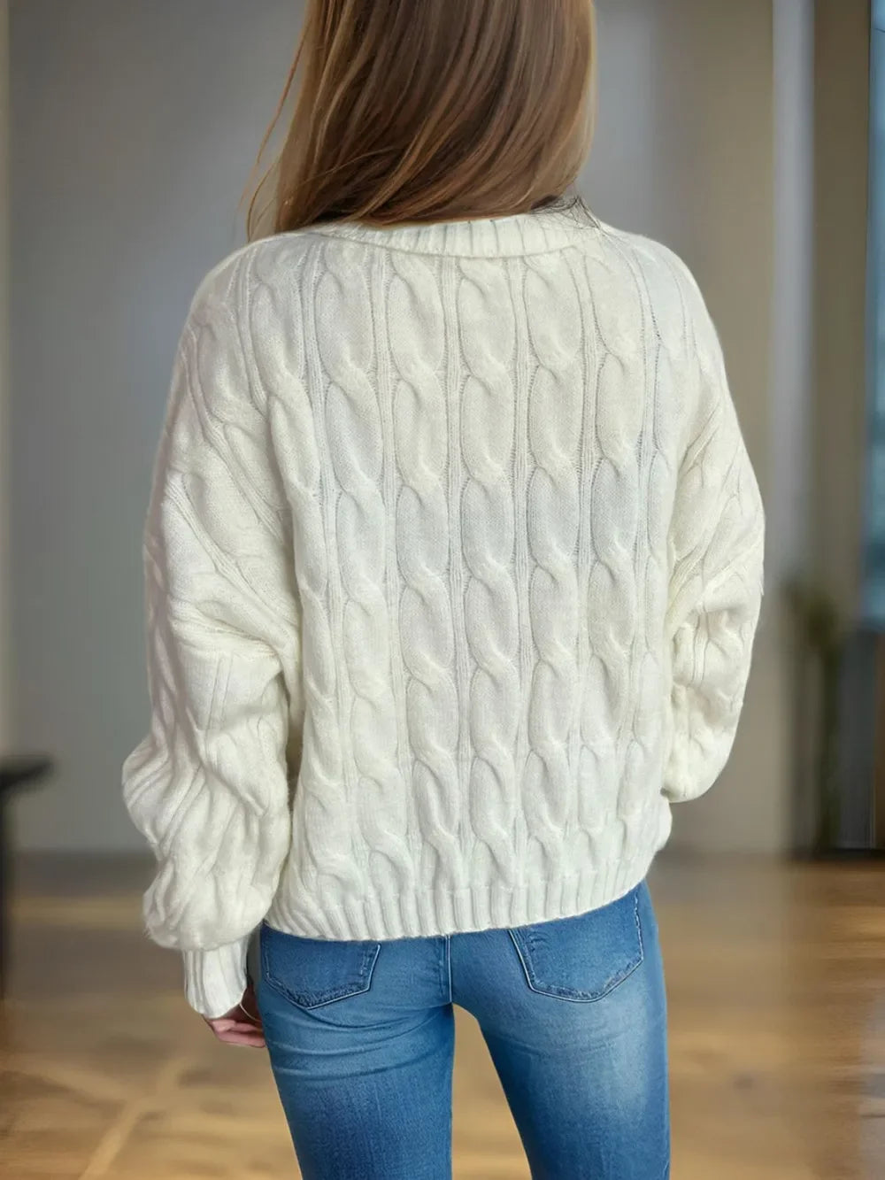 Cream cable-knit turtleneck sweater with blue jeans and long hair