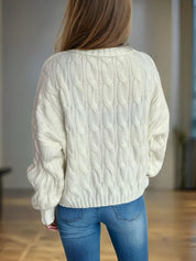 Cream cable-knit turtleneck sweater with blue jeans and long hair