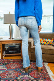 Judy Blue mid-rise thermal bootcut jeans in light blue denim with geometric back pocket and brown wooden clogs
