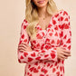 Pink long-sleeved BiBi button-down shirt with red heart print and ruched front