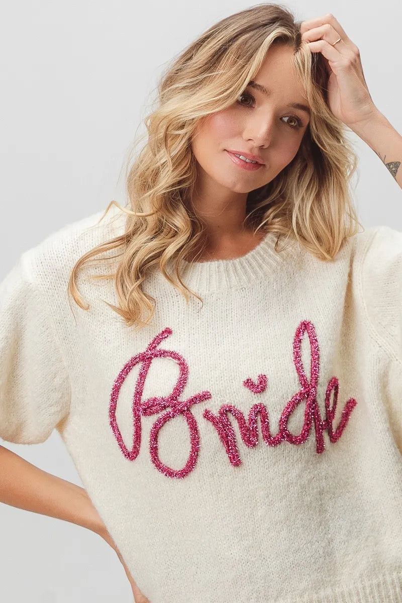 Cream-colored bride sweater with pink sequin lettering and short sleeves