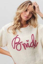 Cream-colored bride sweater with pink sequin lettering and short sleeves