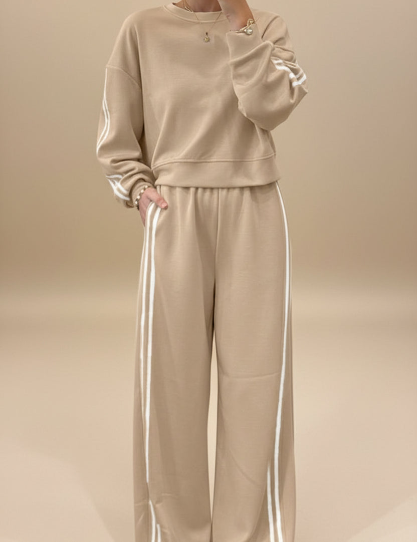 Person wearing a beige tracksuit with white stripes.