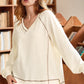 Cream-colored ribbed knit V-neck pullover with exposed gray seam stitching