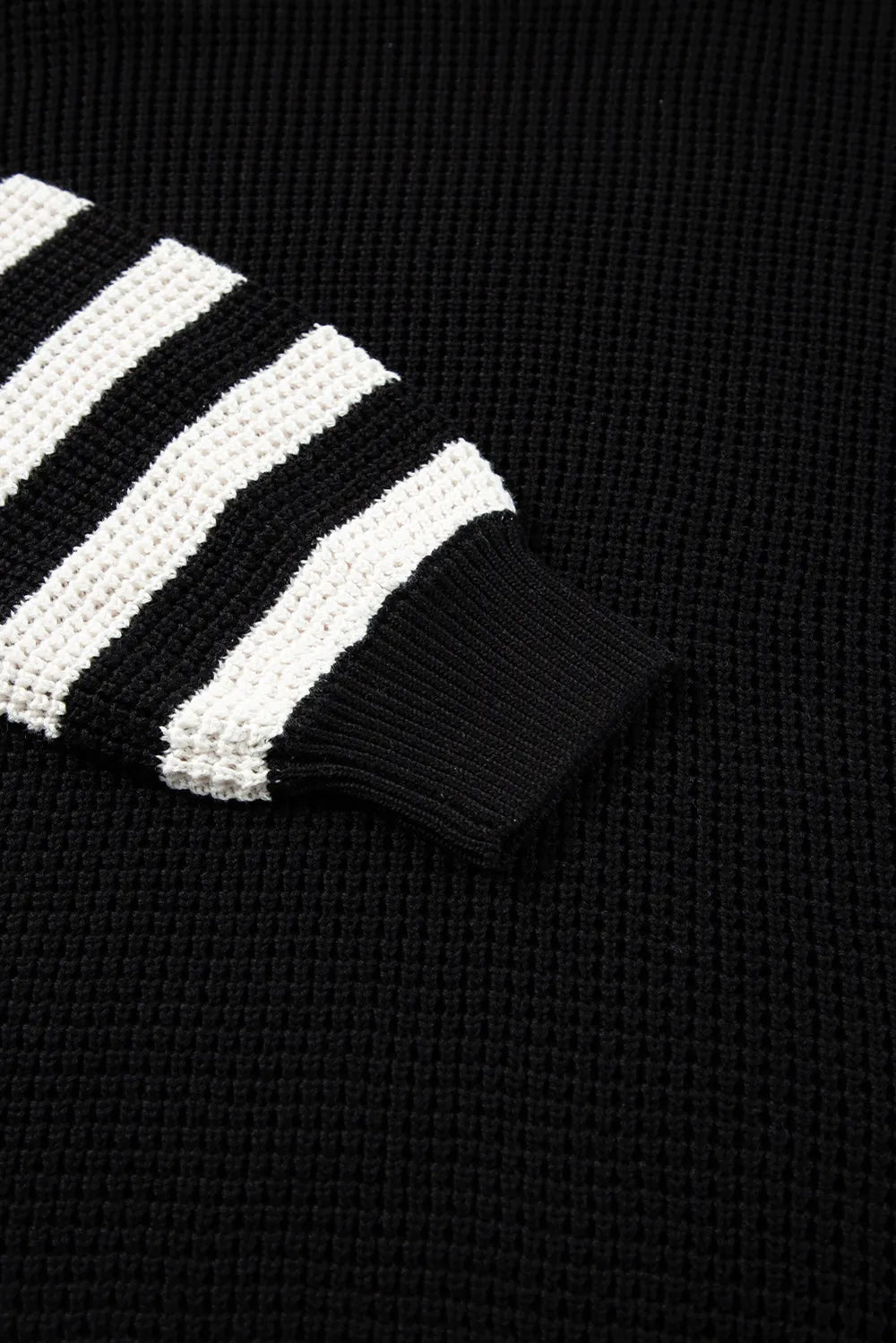 Black and white striped knit sleeve with ribbed cuff on turtleneck sweater