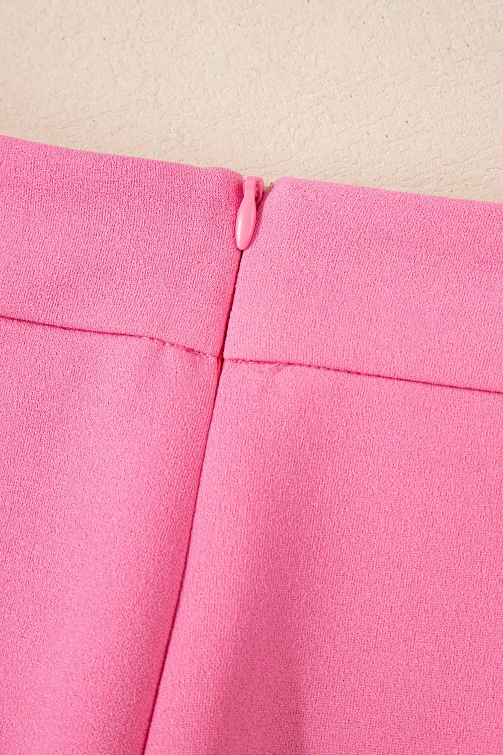 High-waisted bootcut pants with vibrant pink fabric and zipper pull