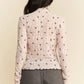 Delicate off-white knit cardigan with black floral pattern and scalloped hem